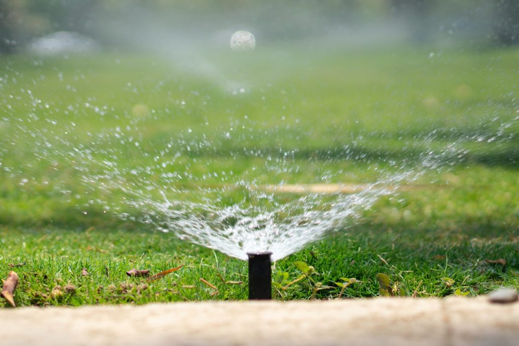 A Sprinkler spraying out water on green grass.
